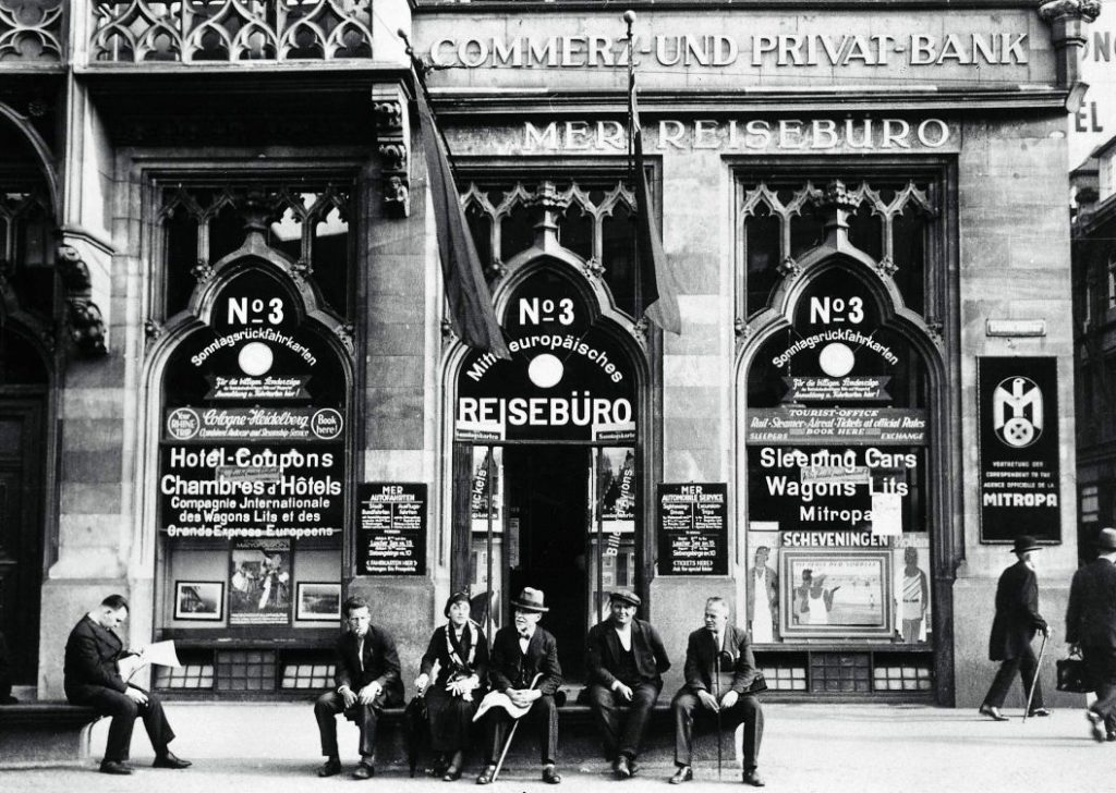 Schwarzweißbild einer Reisebürofassade des MER Reisebüros in Köln von 1930, Menschen sitzen davor