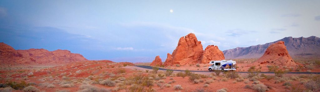 Camper fährt durch eine rote Wüstenlandschaft