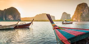 bunte Longtailboote in Thailand, im Hintergrund sind Kalkfelsen zu sehen