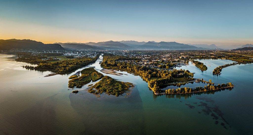 Flussdelta mir einer Stadt im Vordergrund und Bergen im Hintergrund