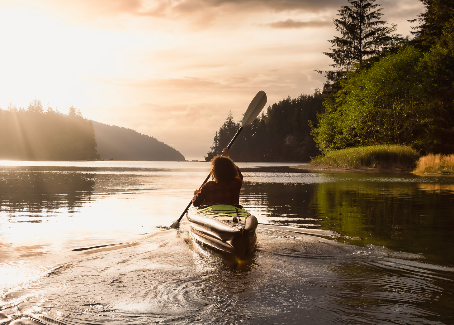 Rückenansicht von einer Frau, die auf einem See oder Fluss paddelt